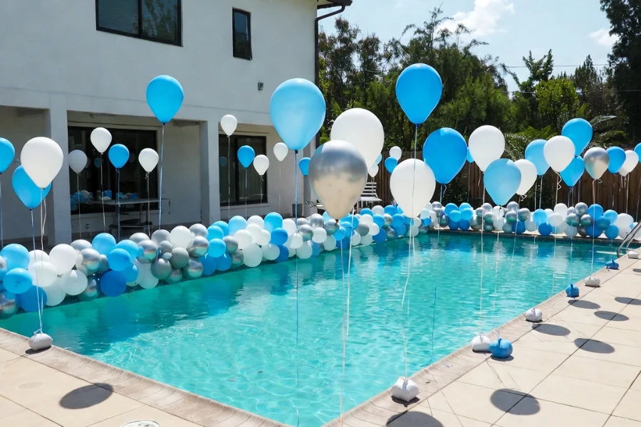Outdoor pool balloon decoration setup with anchored garland and air-filled balloons in a corporate event setting